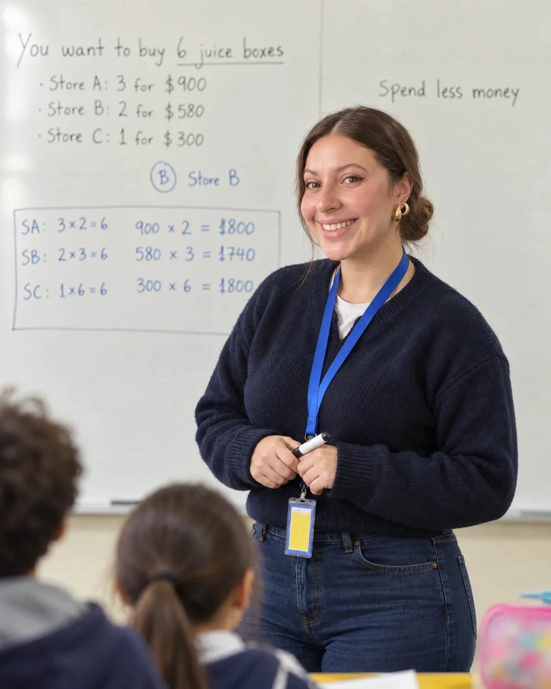 Isidora Benito (Miss Isi) sonríe de frente en su sala de clases, delante de la pizarra con un problema de matemáticas