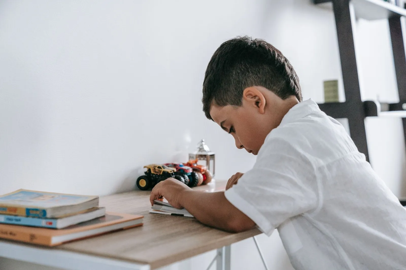 Niño con camisa blanca escribe concentrado en su escritorio